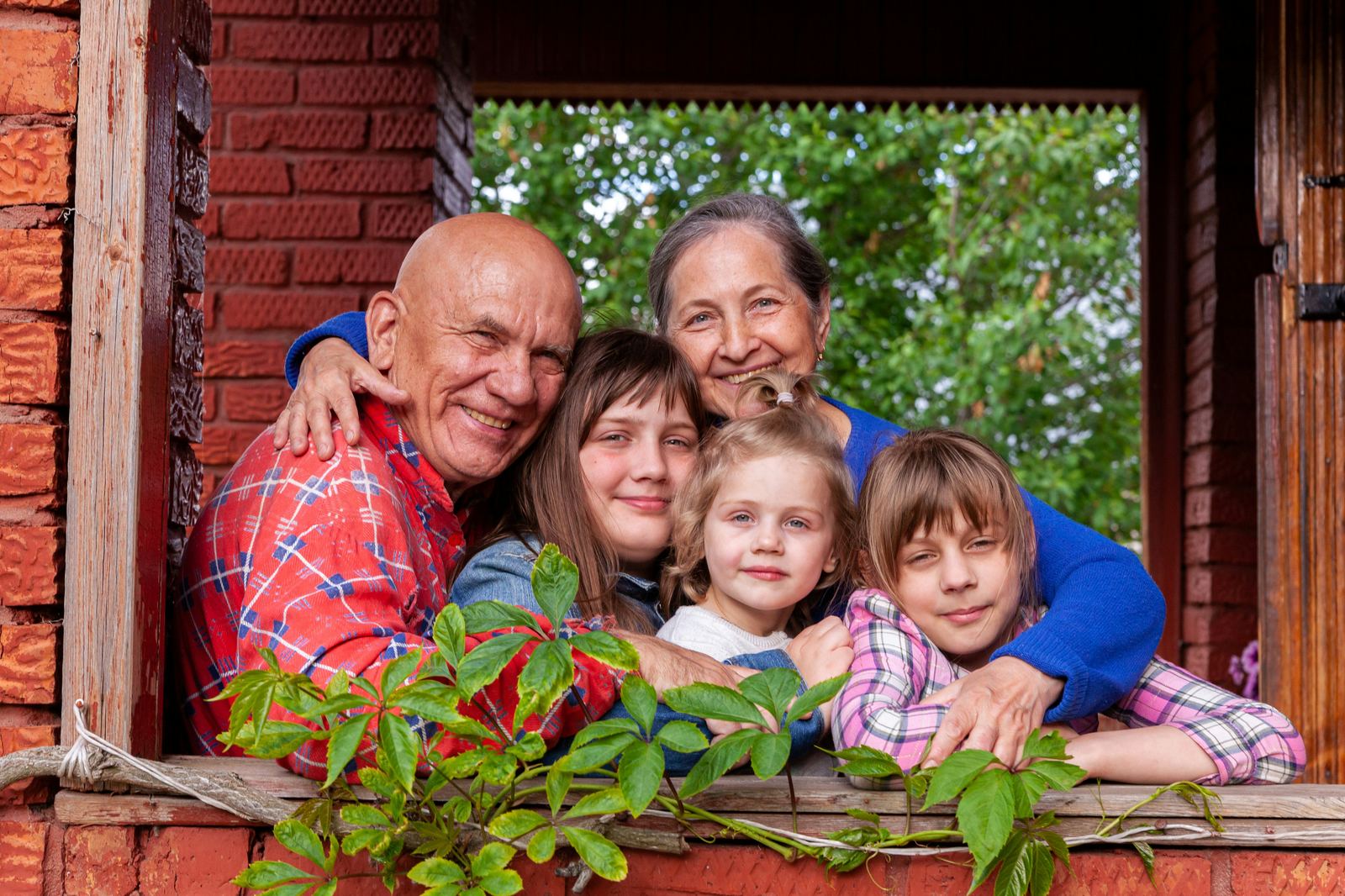 Grandparents embracing three grandchildren at a window